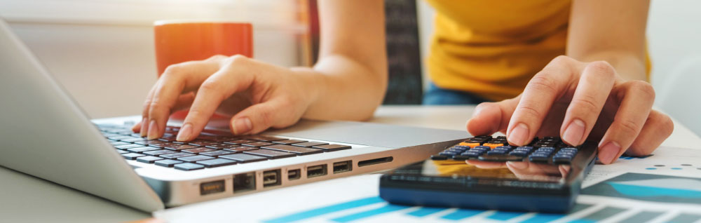 A person is working on accounting with a laptop and calculator