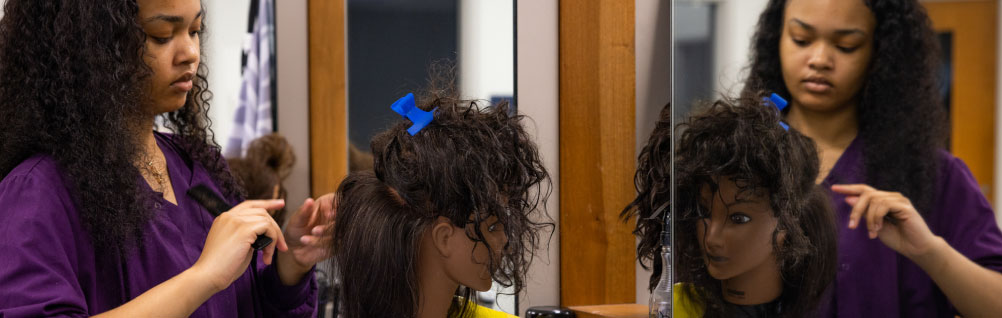 A cosmetology student practicing to become a hair stylist at the Cosmetology school