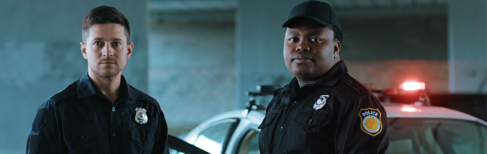 Law enforcement trainees pose in front of a police car