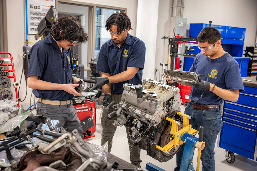 a group of three automotive students at FDTC work on an engine