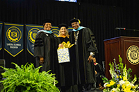 3 people on the stage at graduation