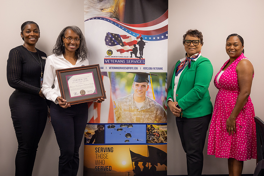 Rudy Williamson, white shirt on left, and Genell Gause, green jacket on right, pose for a picture in the FDTC Veteran's Center with two members of the South Carolina Department of Veterans’ Affairs.