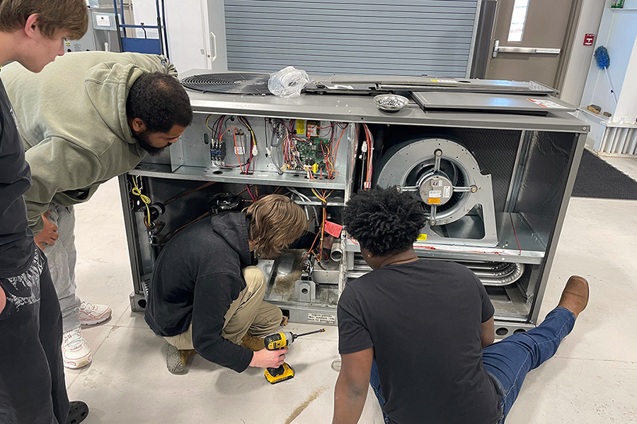 Four Florence-Darlington Technical are looking into a donated commercial gas heating unit in the H V A C lab.