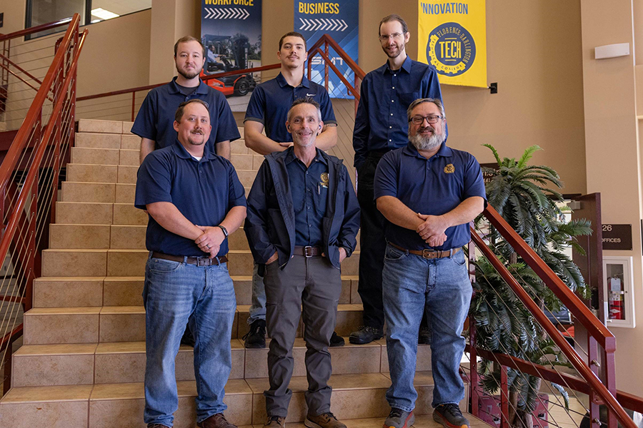 Member of SiMT Manufacturing and Facilities stand on the stairs at the SiMT